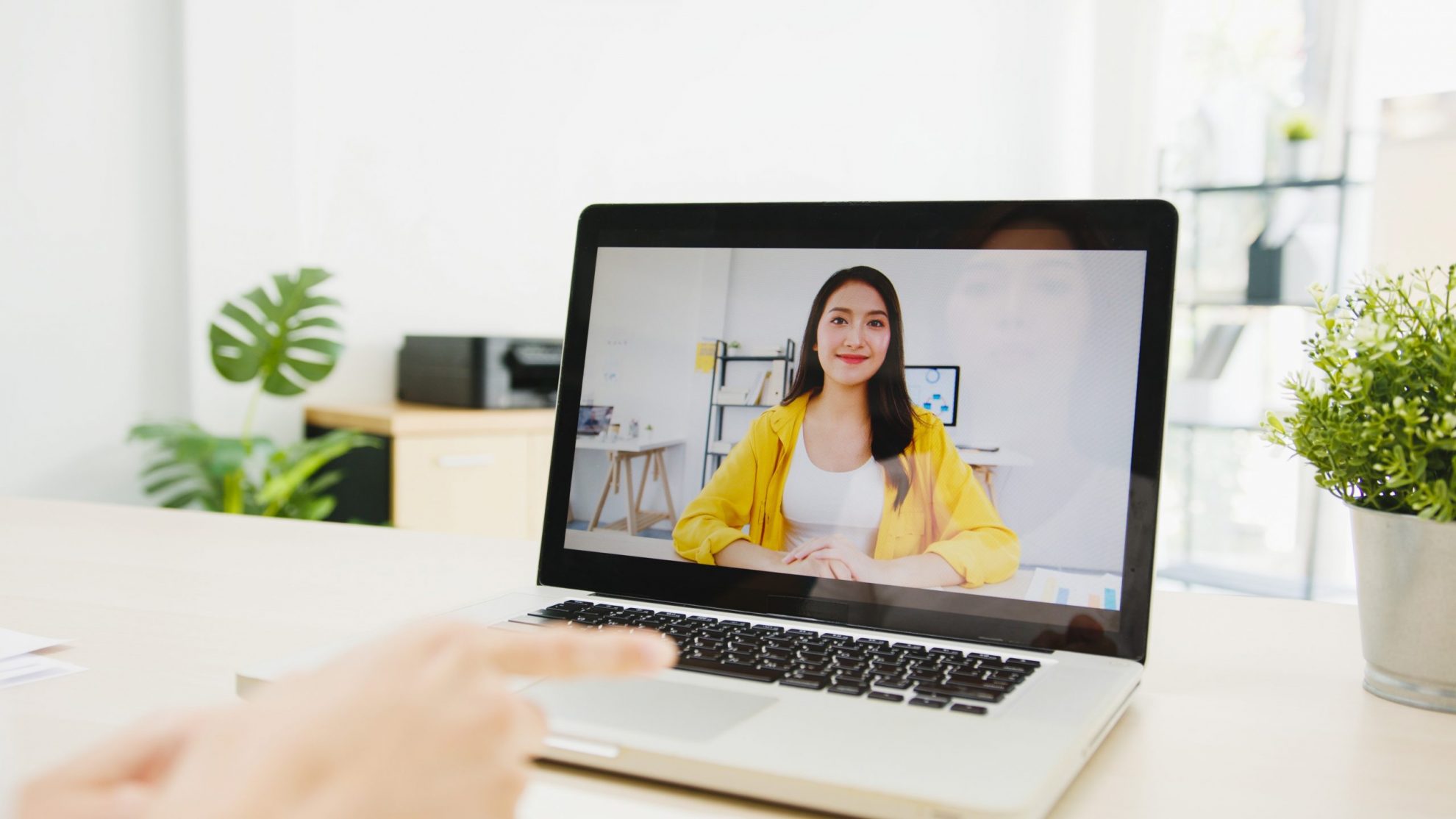 Photo of woman smiling on computer screen illustrates blog: "15 Questions You Should Ask When Hiring for a Remote Position"