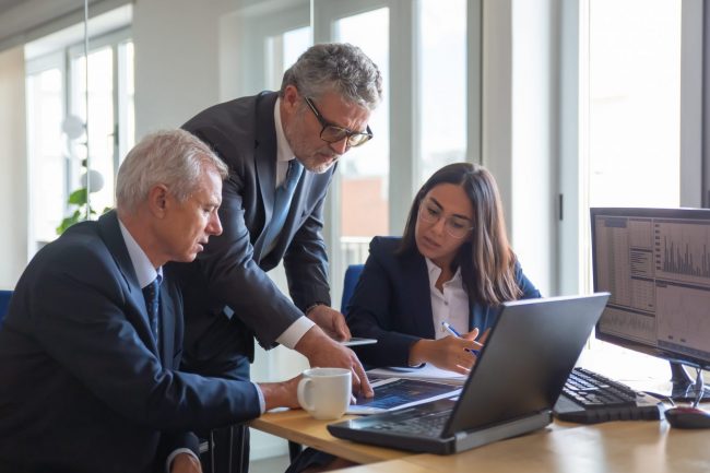 Photo of workers sitting at desk illustrates blog: "From the Great Resignation to the Great Retirement: the Job Trends You Need to Know"
