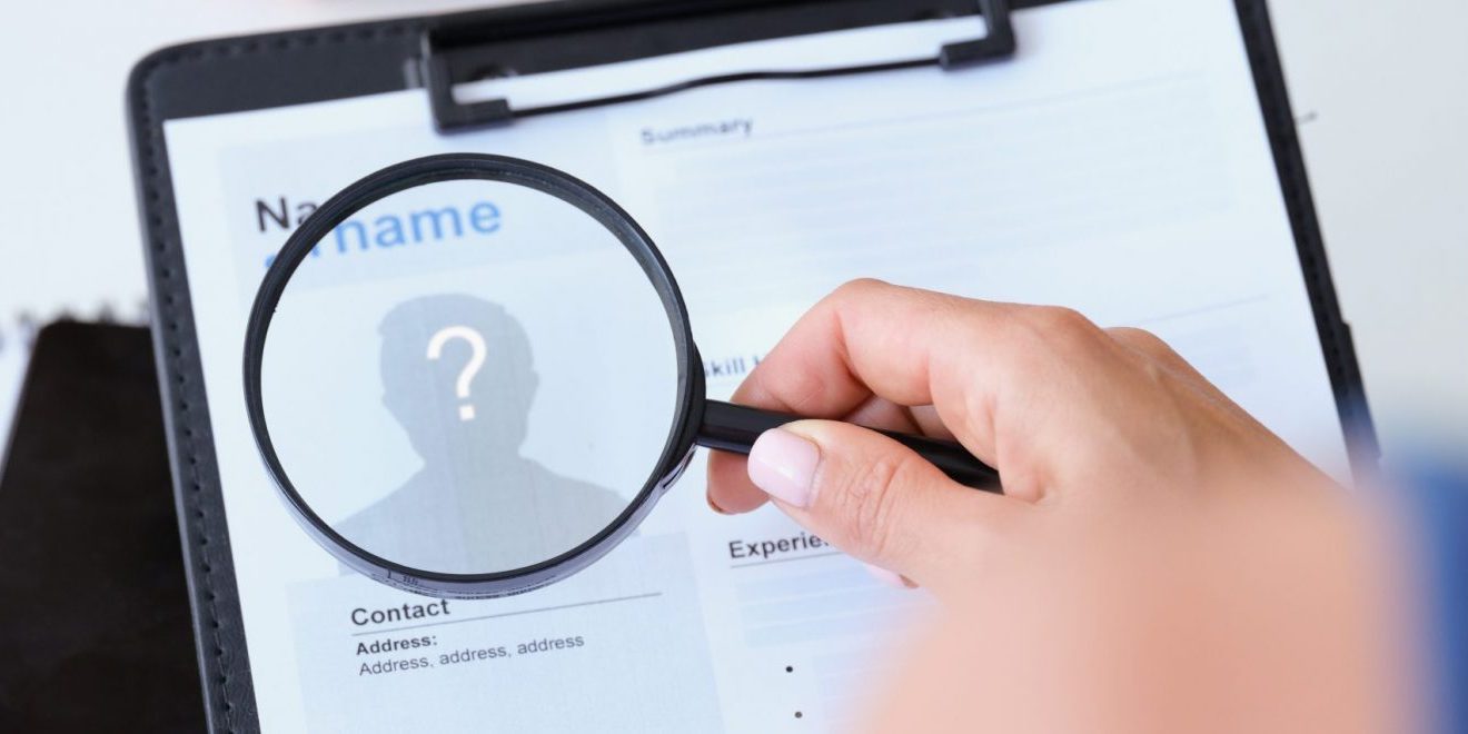 Photo of hand holding magnifying glass over resume illustrates blog: "Are Background Checks Accurate?"