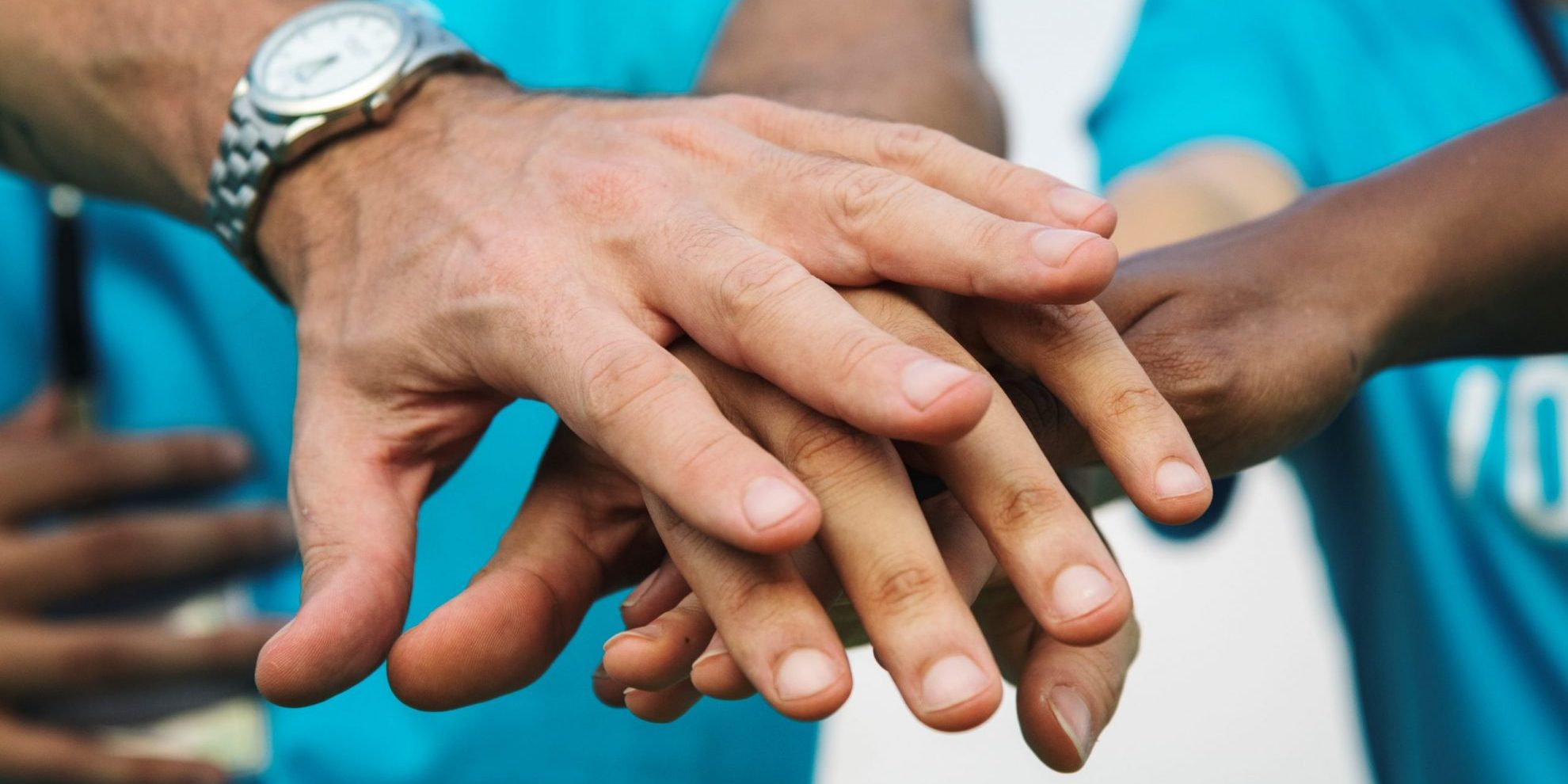 Photo of team putting hands together illustrates blog: "Background Checks for Volunteers"