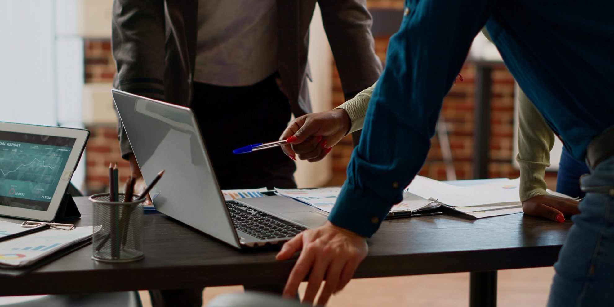 Photo of three people looking at laptop illustrates blog:; "How Long Does It Take To Complete a Background Check?"