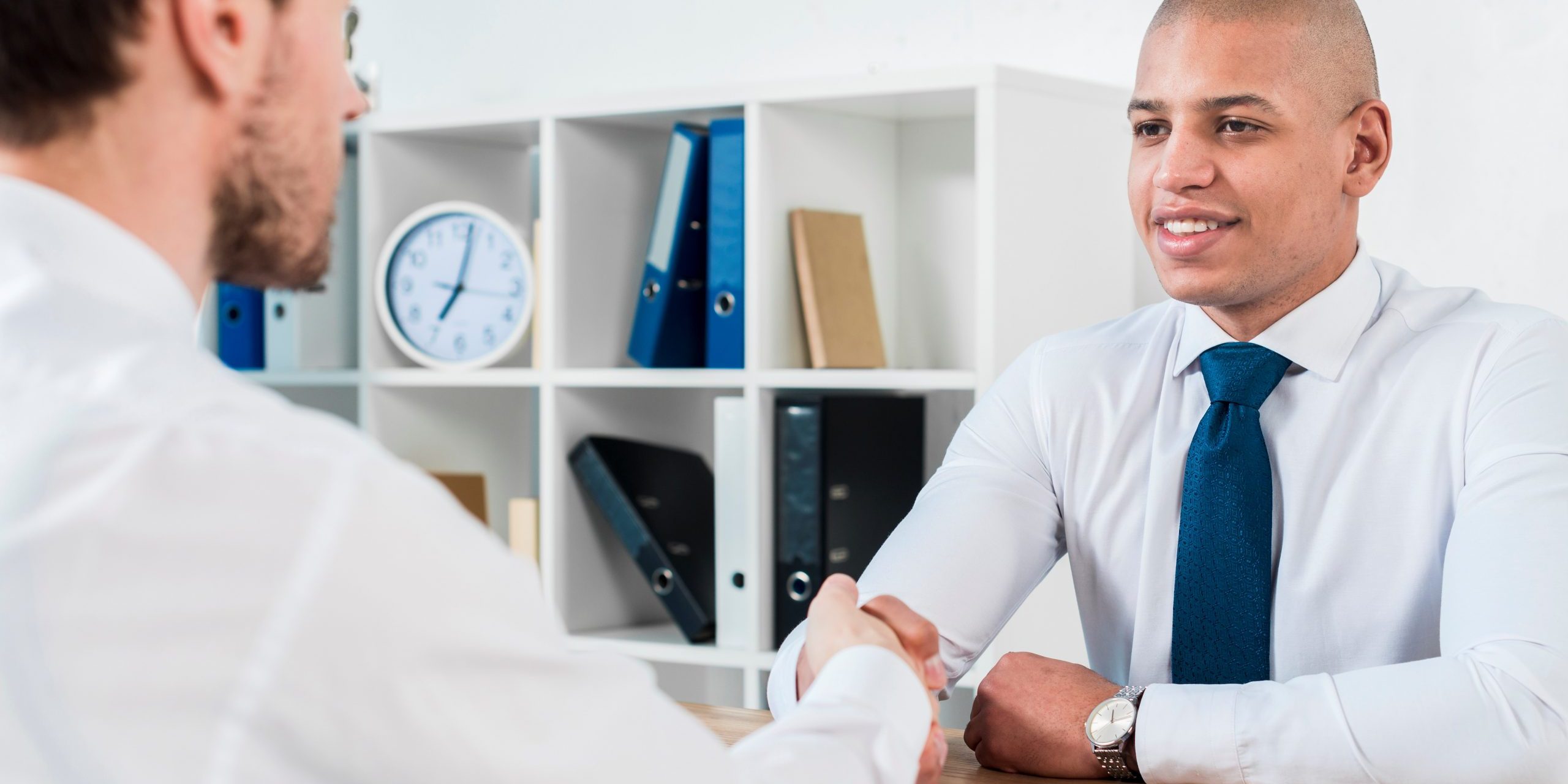 Men shaking hands in office illustrate blog "Exploring Alternative Talent Pools for Your Company"