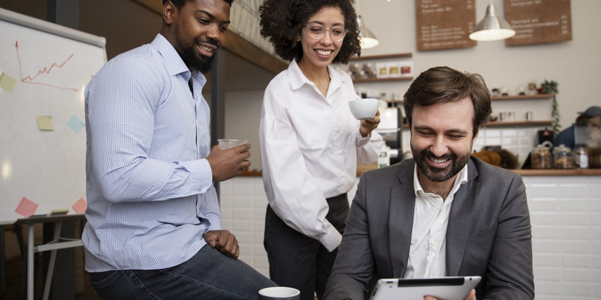 Group of three people looking at tablet illustrates blog "What Is DEI in the Workplace?"