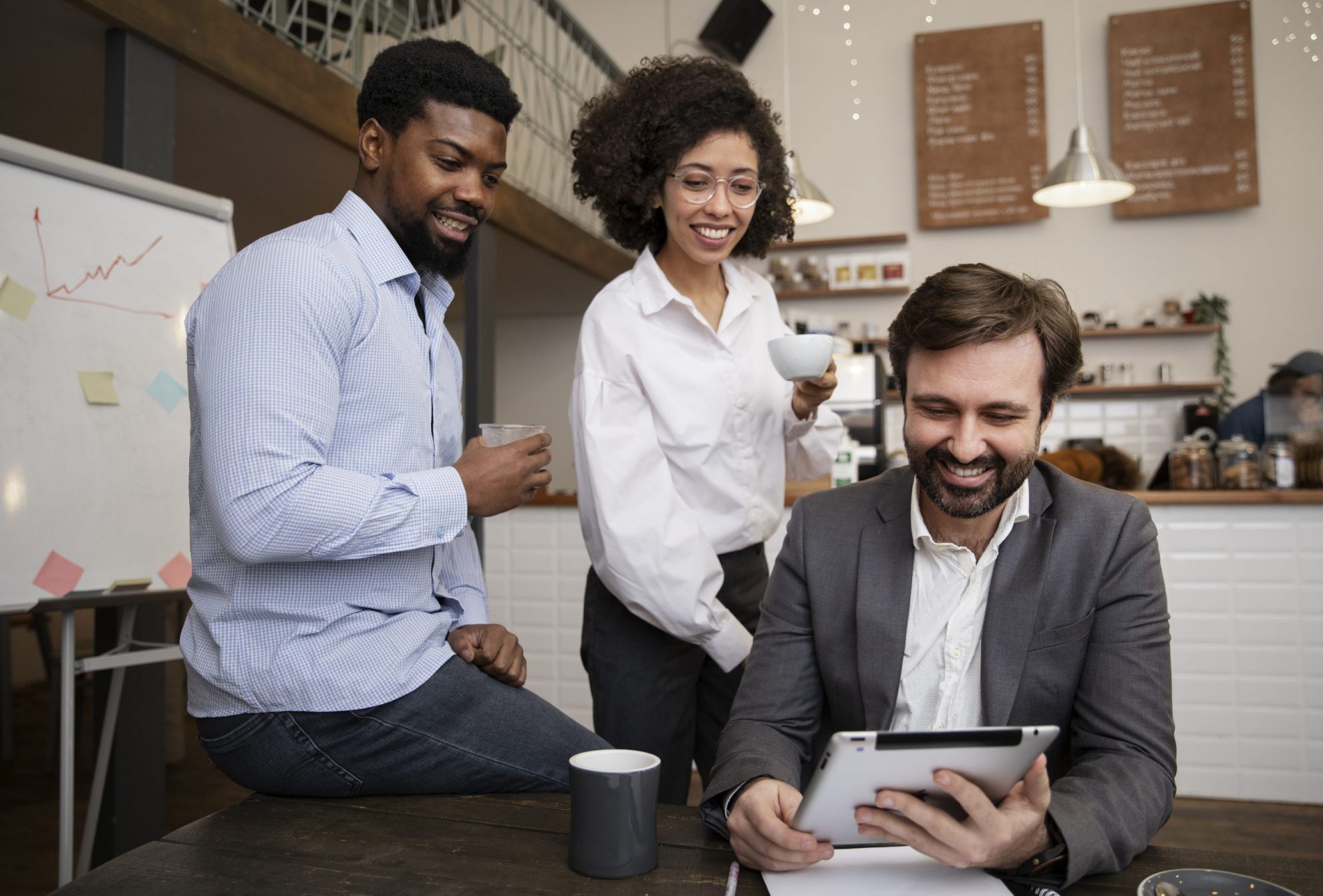Group of three people looking at tablet illustrates blog "What Is DEI in the Workplace?"