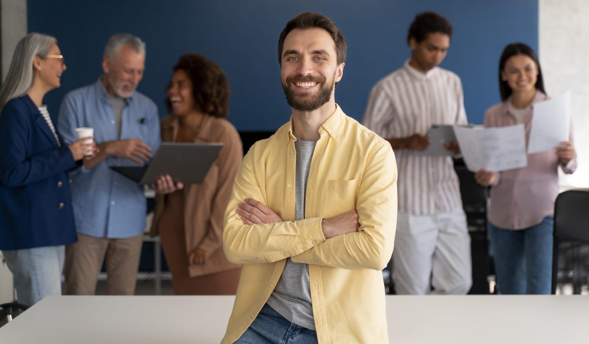 Man sitting on desk with people in the background illustrates blog "When To Run Background Checks?"