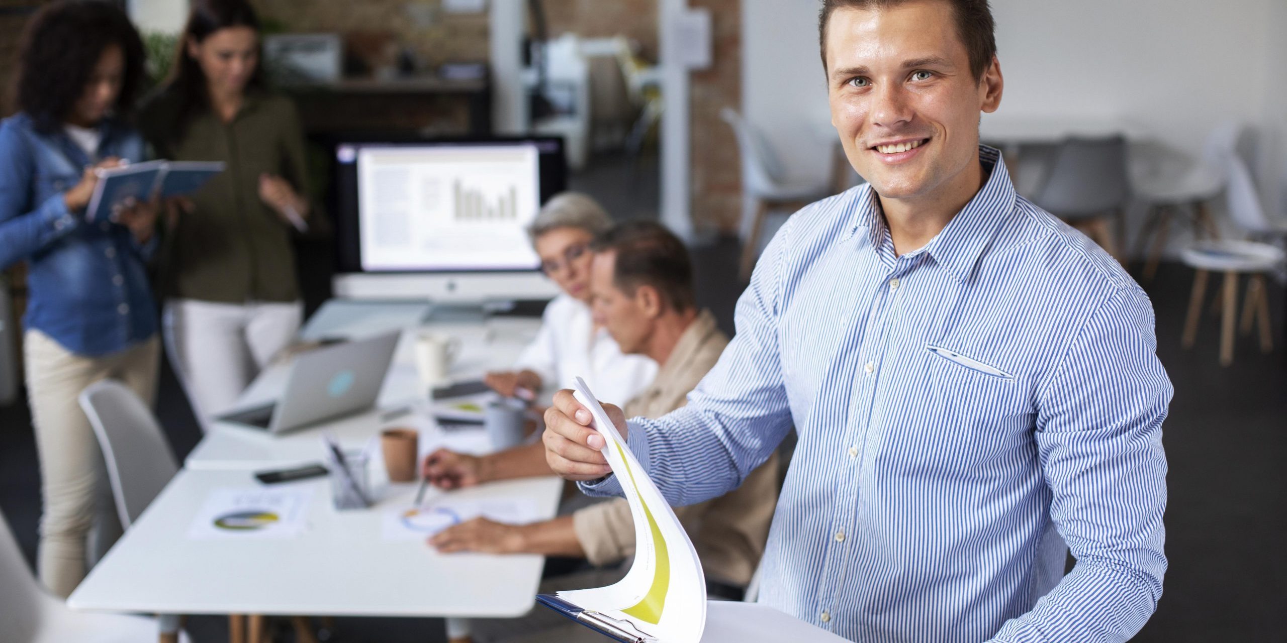 Man in office holding clipboard illustrates blog "Internal Gigs and Background Screening"