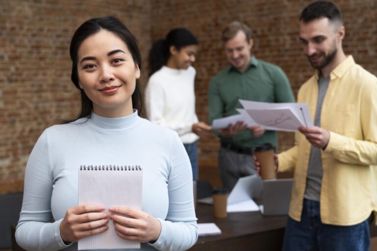 Woman holding notebook with people in the background in office.