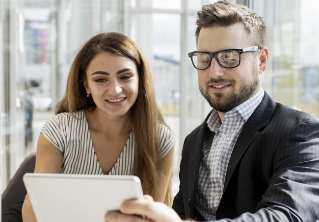 Woman and man looking at tablet illustrate blog "Background check vs Reference Check: "What Is the Difference?"