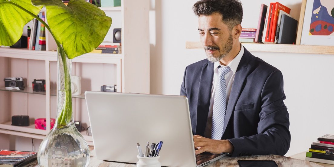 Man in office typing on laptop illustrates blog "5 Background Screening Trends You Need To Know"
