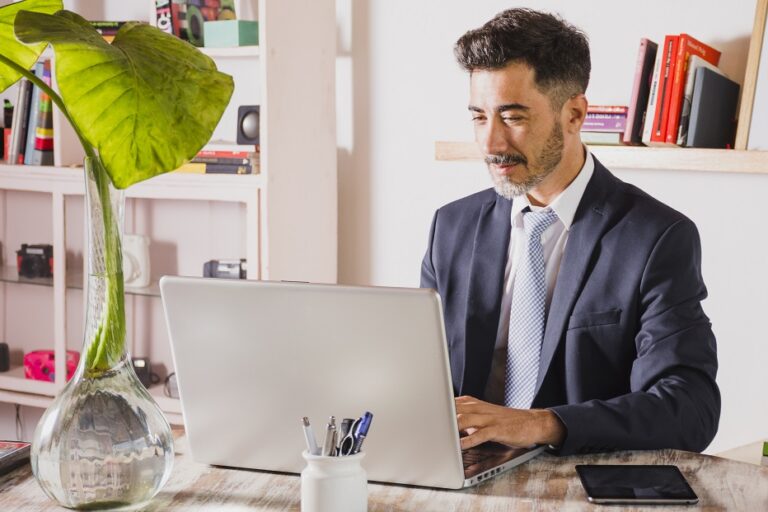 Man in office typing on laptop illustrates blog "5 Background Screening Trends You Need To Know"