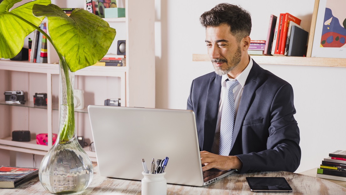 Man in office typing on laptop illustrates blog "5 Background Screening Trends You Need To Know"